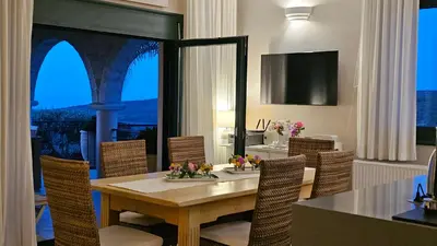 a dining room with a table and chairs and a television at Villa Europa - Western Crete - Chania in Darmarochori