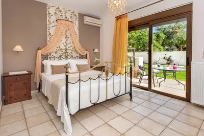 a bedroom with a canopy bed and a patio at Cretan Blu Platanias in Plataniás