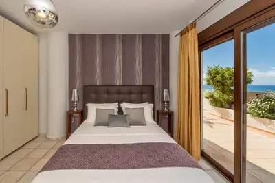 a bedroom with a bed and a view of the ocean at Cretan Blu Platanias in Plataniás