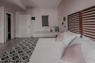 a bedroom with a large white bed with pink pillows at Tellus City in Chania Town
