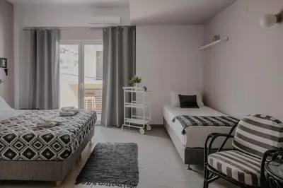 a bedroom with two beds and a chair and a window at Tellus City in Chania Town