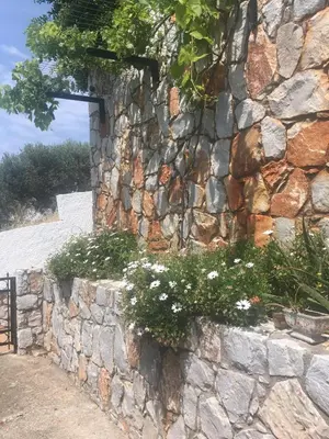 a stone wall with flowers on it at Maria's Garden in Galatás