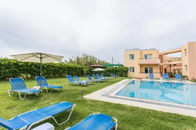 a group of blue lounge chairs and a swimming pool at Alonia Hotel Apartments in Kolymvari