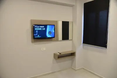 a television on a wall in a white room at Pirgos Deluxe Apartment - Private Parking in Kissamos