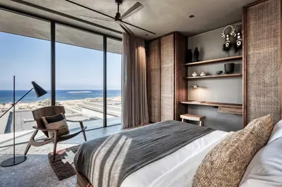 a bedroom with a bed and a view of the ocean at Domes Zeen Chania, a Luxury Collection Resort, Crete in Kato Daratso