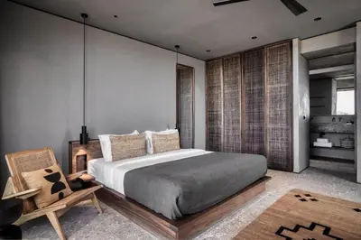 a bedroom with a large bed and a chair at Domes Zeen Chania, a Luxury Collection Resort, Crete in Kato Daratso