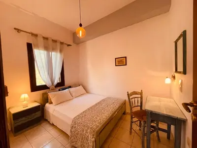 a bedroom with a bed and a table and a window at Brina's House in Kissamos