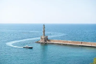 a boat in the water next to a lighthouse at Alexandra's Lighthouse View in Chania Town