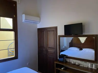 a bedroom with a bed with a mirror and a tv at Captain Vasilis Hotel in Chania Town
