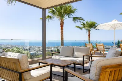 a patio with chairs and tables and palm trees at Karmilos Hill Villa in Chania Town