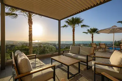 a patio with a couch and chairs and palm trees at Karmilos Hill Villa in Chania Town
