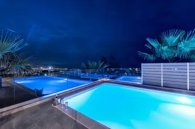 a swimming pool at night with palm trees at Karmilos Hill Villa in Chania Town