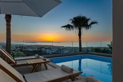 a villa with a swimming pool and a sunset at Karmilos Hill Villa in Chania Town
