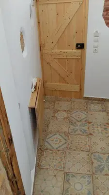 a bathroom with a wooden door and a tile floor at Green Door Apartment in Chania Town