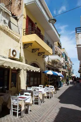 a group of tables and umbrellas on a city street at Green Door Apartment in Chania Town