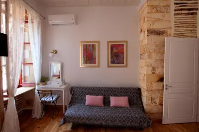 a living room with a couch with two pink pillows at Green Door Apartment in Chania Town