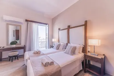 a bedroom with two beds and a large window at Kalamaki Mare Suites in Kalamaki Chanion