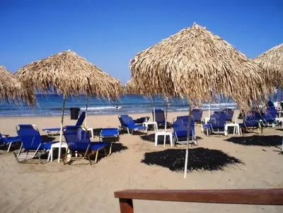 a group of chairs and straw umbrellas on a beach at Kalamaki Mare Suites in Kalamaki Chanion