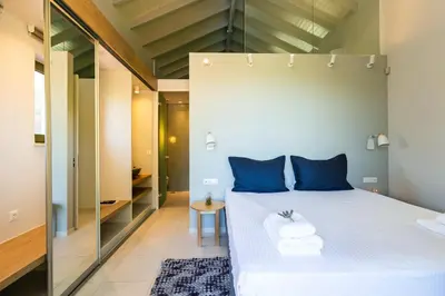 a bedroom with a bed with blue pillows and a mirror at Physis Villas Chania in Ayiá