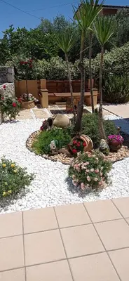 a garden with palm trees and flowers on a sidewalk at Antony Home in Kounoupidhianá