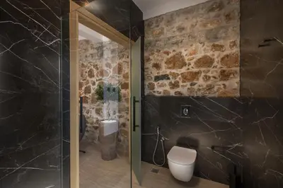 a bathroom with a toilet and a stone wall at Agave Suites in Chania Town