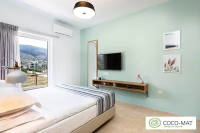 a bedroom with a bed and a tv and a window at Ethereal Apartments Chania in Souda