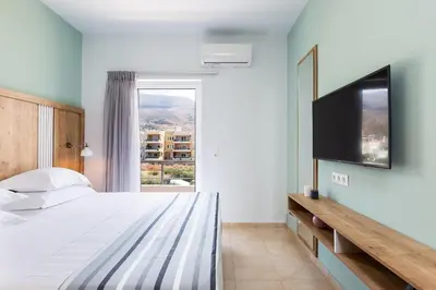 a bedroom with a bed and a flat screen tv at Ethereal Apartments Chania in Souda