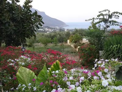a garden with flowers and the ocean in the background at Chrissi's house with garden and sea view Zerviana in Kissamos