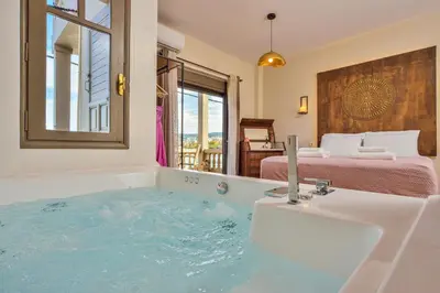 a bathroom with a tub with a sink and a bed at East Seafront Suite in Chania Town