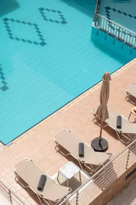 an overhead view of a swimming pool with lounge chairs and an umbrella at Thelèsi Apartments, 100m from the beach in Stalos