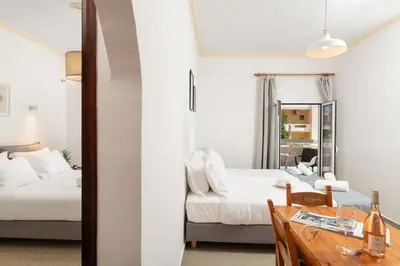a bedroom with two beds and a table and a mirror at Thelèsi Apartments, 100m from the beach in Stalos