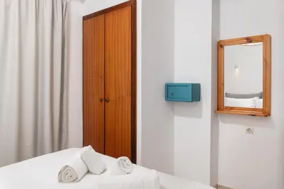 a bedroom with a mirror and a bed with towels at Thelèsi Apartments, 100m from the beach in Stalos