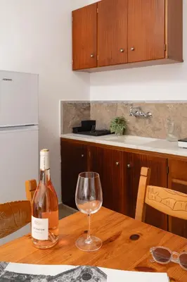 a bottle of wine sitting on a wooden table with a wine glass at Thelèsi Apartments, 100m from the beach in Stalos