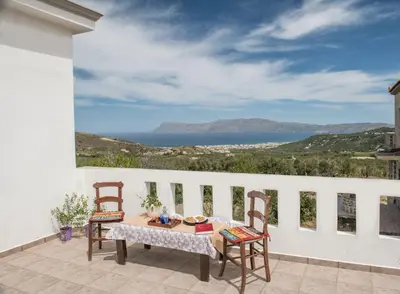 a table and chairs on a balcony with a view of the ocean at Kyparissos Apartment I in Kissamos