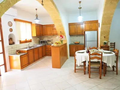 a large kitchen with a table and a refrigerator at Traditional Cretan Villa in Rodhopós