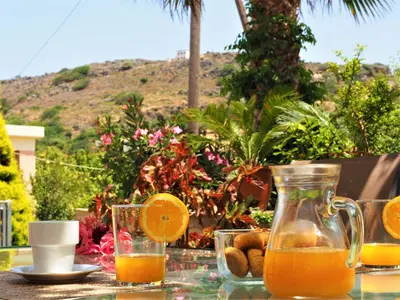 a glass table with orange juice and oranges on it at Traditional Cretan Villa in Rodhopós