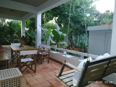 a porch with a swing and a table and chairs at Zacharoula's Home in Chania Town