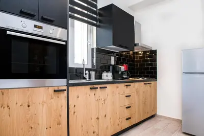 a kitchen with wooden cabinets and black appliances at Elegant Apartment in Chania Town