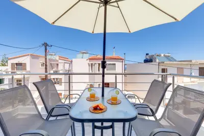 a table with two drinks and an umbrella on a balcony at Ikia Aretousa in Kato Daratso