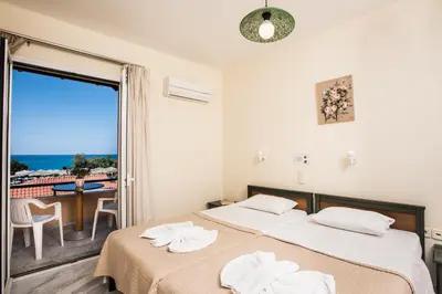 two beds in a room with a view of the ocean at Mythos Beach Hotel Apartments in Maleme