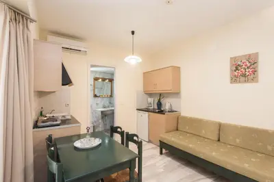 a living room with a couch and a table and a kitchen at Mythos Beach Hotel Apartments in Maleme