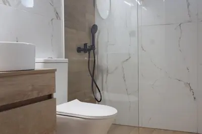 a bathroom with a shower with a toilet and a shower head at Villa Elea Apartments in Spiliá