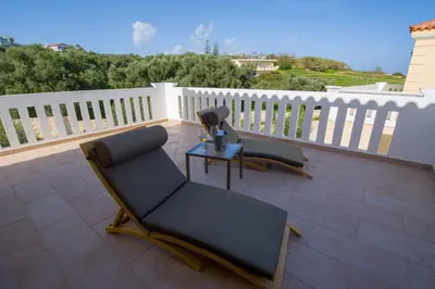 a patio with two chairs and a table on a balcony at Casa Leone Suites in Stalos