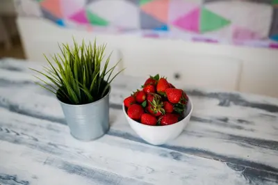 two bowls of strawberries and a potted plant on a table at Pixelart Home in Kounoupidhianá