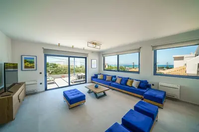 a living room with a blue couch and chairs and windows at Naval villa-Panoramic villa with heated pool on the roof in Gerani Chanion