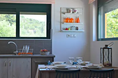 a kitchen with a table with plates and wine glasses at Aspalathos Villas in Fílippos