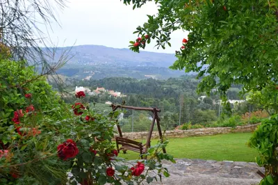 a wooden chair sitting in a garden with roses at Aspalathos Villas in Fílippos