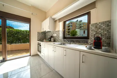 a kitchen with white cabinets and a large window at Iro City and Beach Boutique Homes in Chania Town