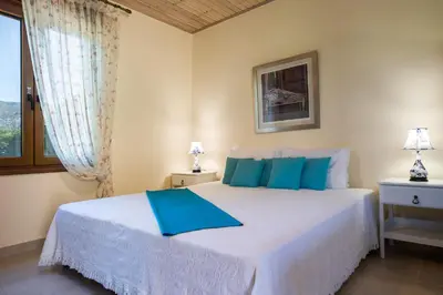 a bedroom with a large white bed with blue pillows at Villa Anerocurù by Chania city in Chania Town