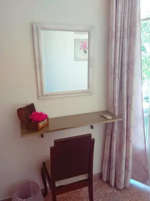 a mirror on a wall next to a window with a chair at The Manor House in the Old Town in Chania Town